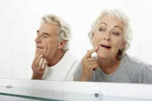 Senior Couple Looking At Reflections In Mirror For Signs Of Ageing
