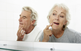 Senior Couple Looking At Reflections In Mirror For Signs Of Ageing